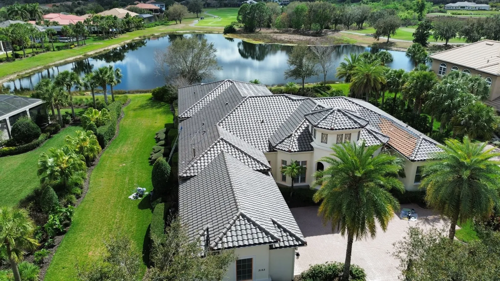 Aerial view of a lakefront estate with a gray tile roof