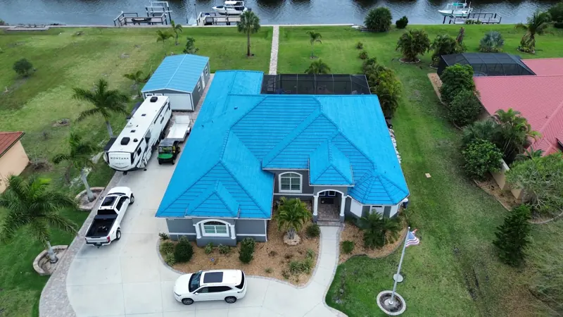 Aerial view of a waterfront home with a blue metal roof