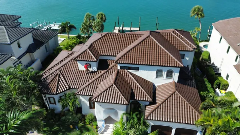 Aerial view of a painter on the tile roof of a waterfront estate in Sarasota, FL