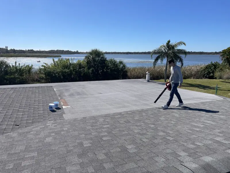 Flat roof painting in progress on a lakefront home, white finish being applied