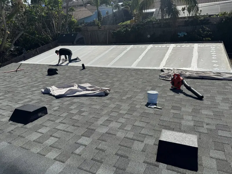Flat roof section before painting next to a shingle roof