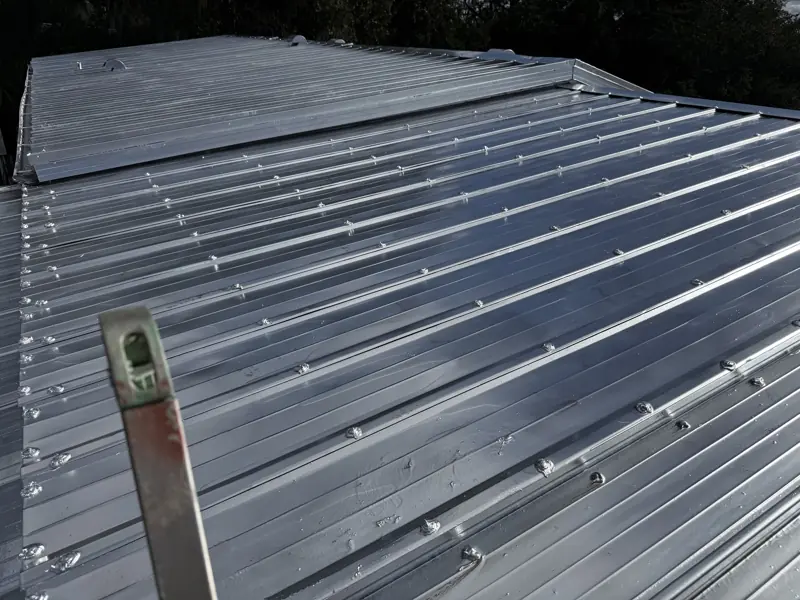 Metal roof after painting silver on a wooded lot
