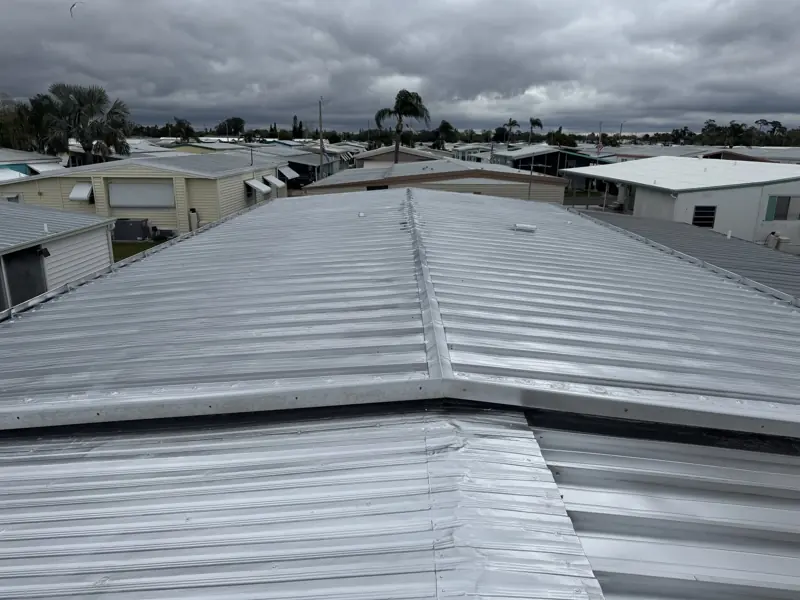 Silver painted metal roof in a mobile home community under cloudy skies