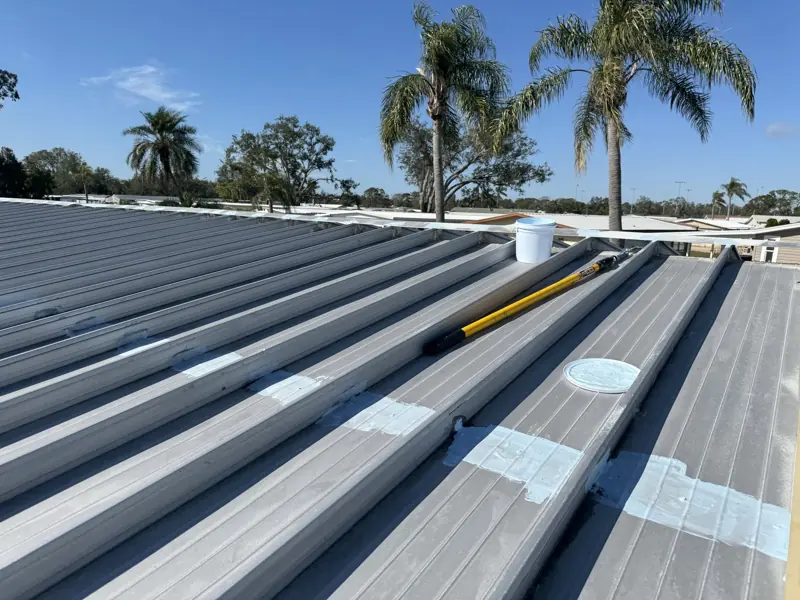 Metal roof painting in progress with tools on the roof