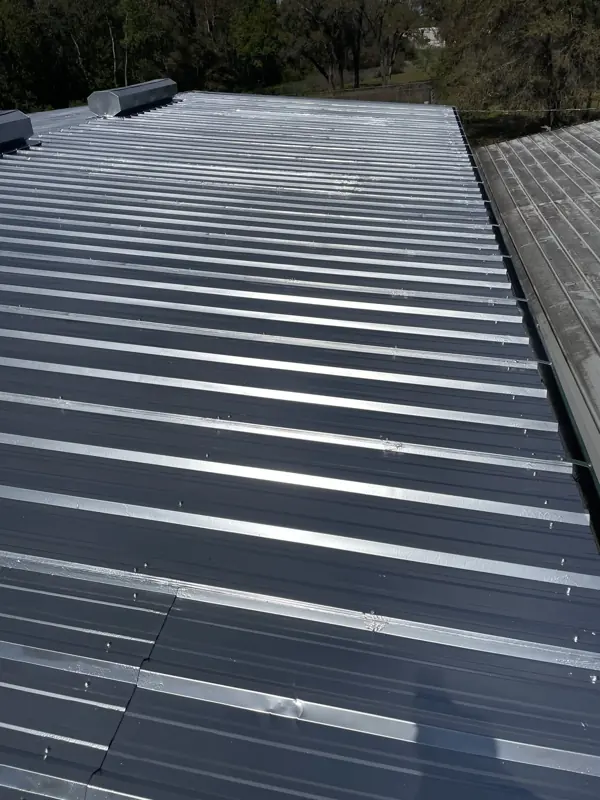 Mobile home metal roof after painting in a uniform silver finish