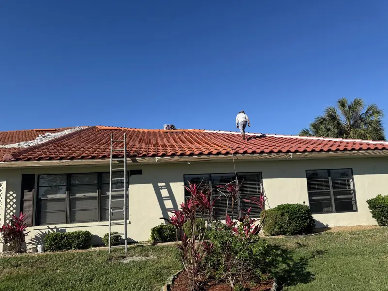 Painter on a terracotta tile roof of a stucco home