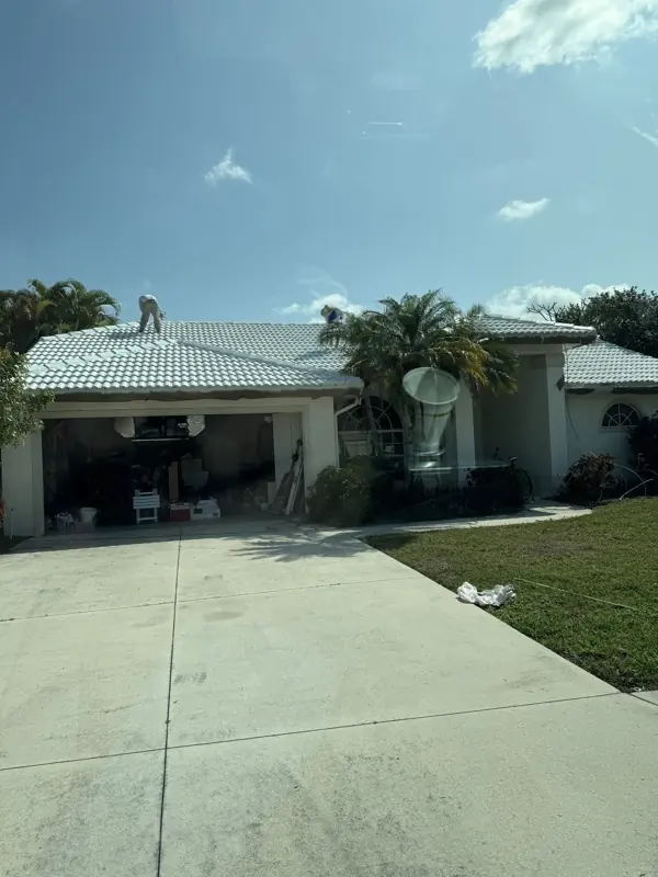 Painter working on a white tile roof of a Florida ranch home