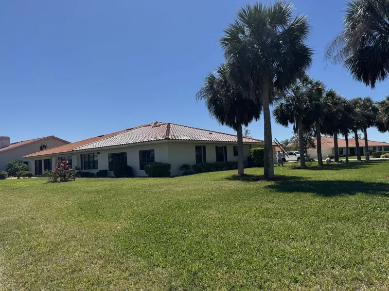 Stucco home with freshly painted terracotta tile roof, lawn view