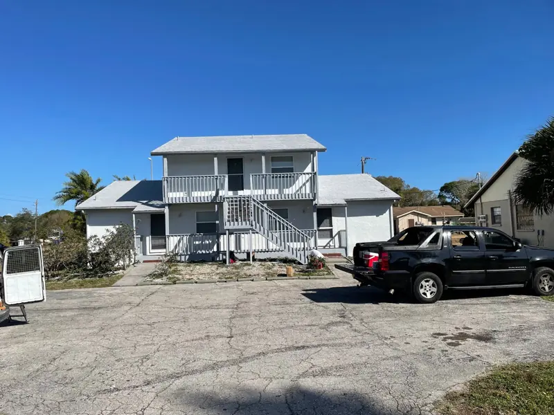 Front of a two-story duplex after exterior painting, white stucco and new railings