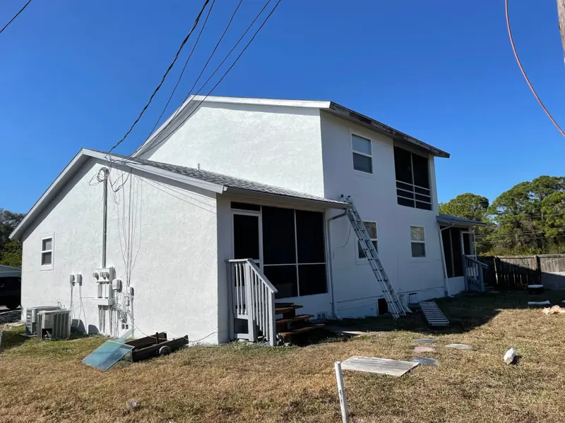 Rear of a two-story stucco duplex after exterior painting in fresh white
