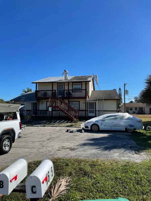 Front of a two-story duplex before exterior painting, worn tan stucco