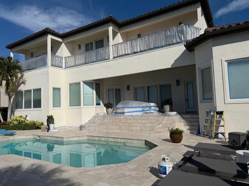 Two-story white home with pool during exterior painting