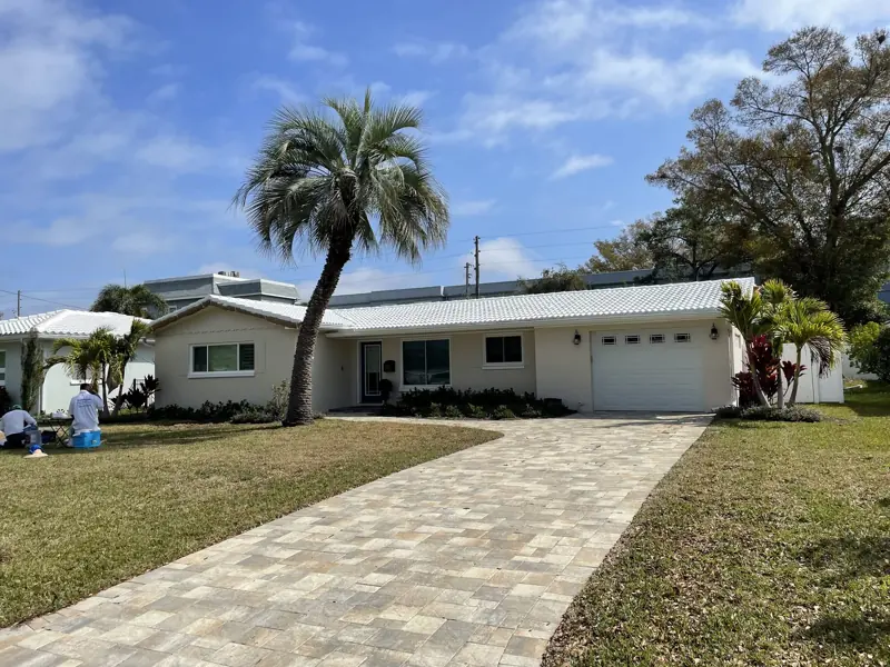 White ranch home with a white tile roof after painting