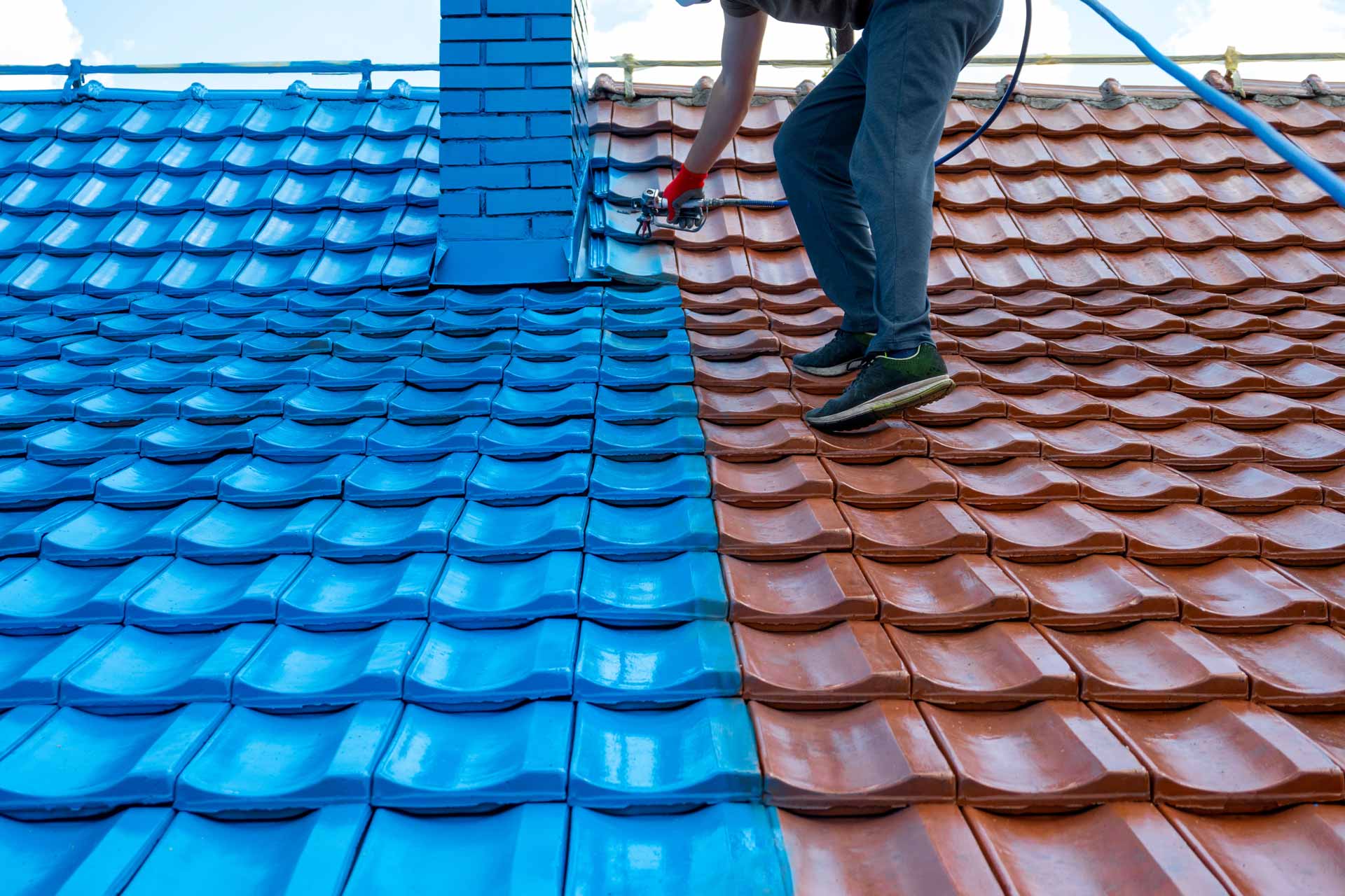 Candid shot of man painting clay tile roof bright blue