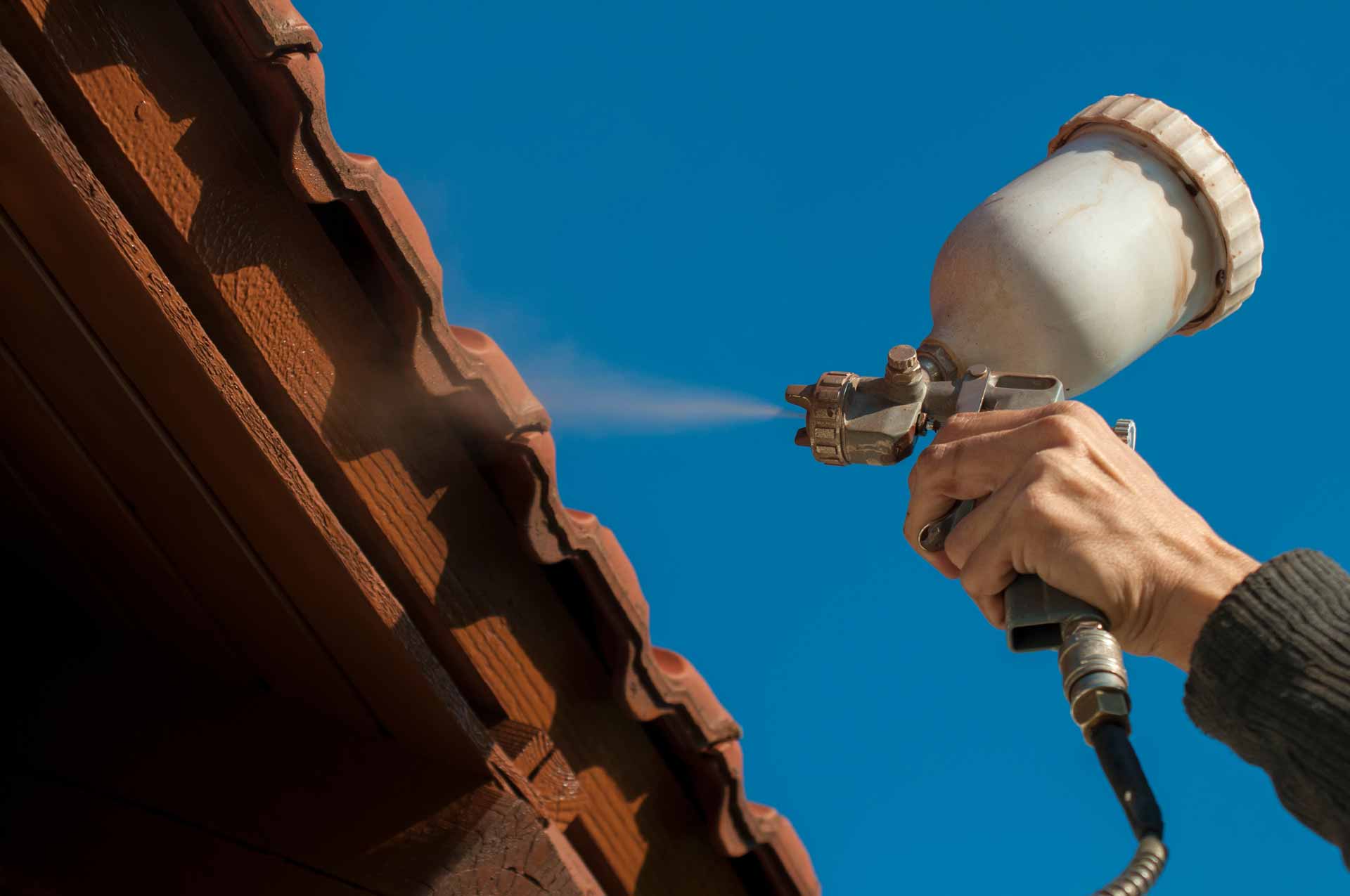 Spraying paint on clay tile roof